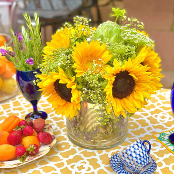 Sunflower arrangement in a clear glass vase on a patterned table