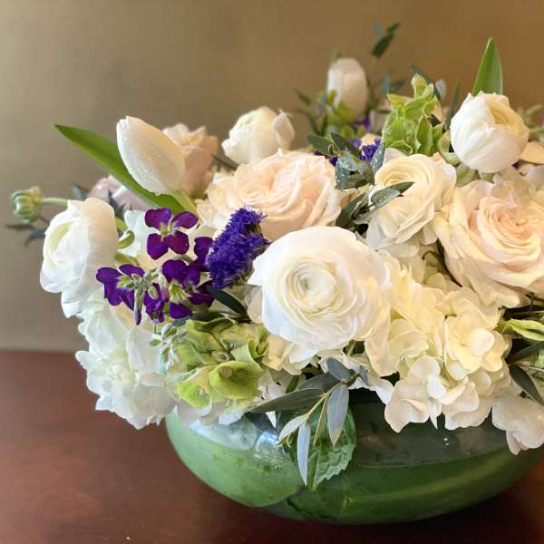 White and blush flowers arranged in a green glass bowl