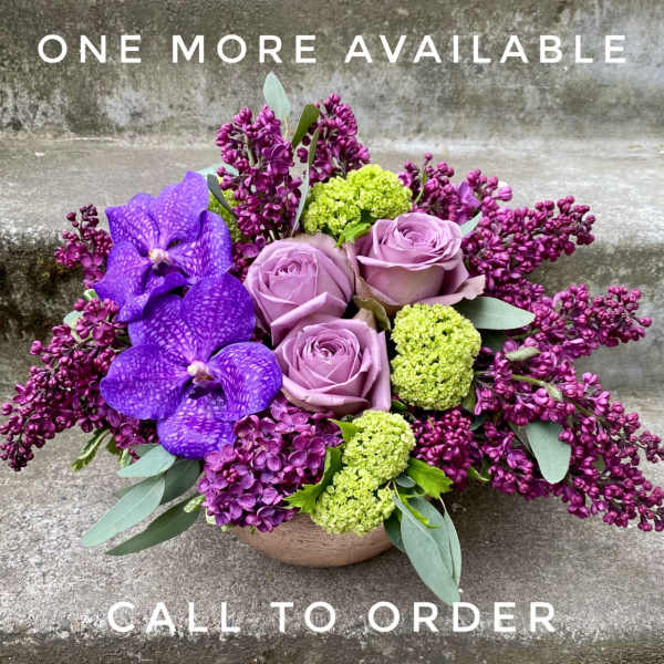 Purple orchids and lavender roses in a low bowl arrangement