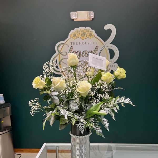 Cream rose arrangement in a silver vase with baby's breath