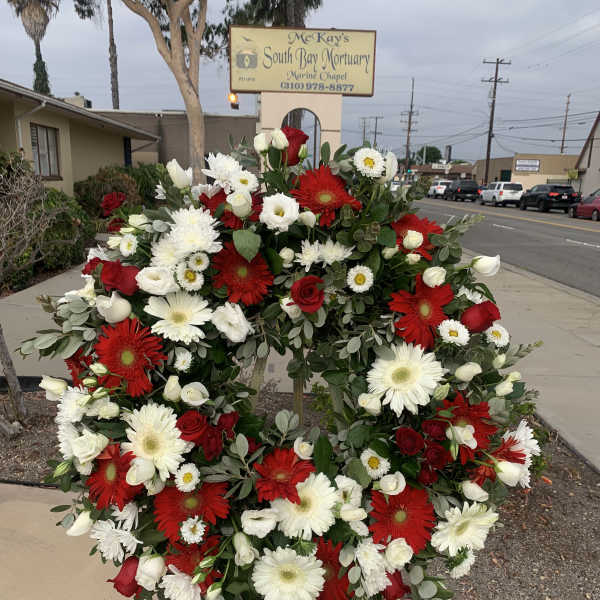 Large red, white, and green funeral wreath on a stand