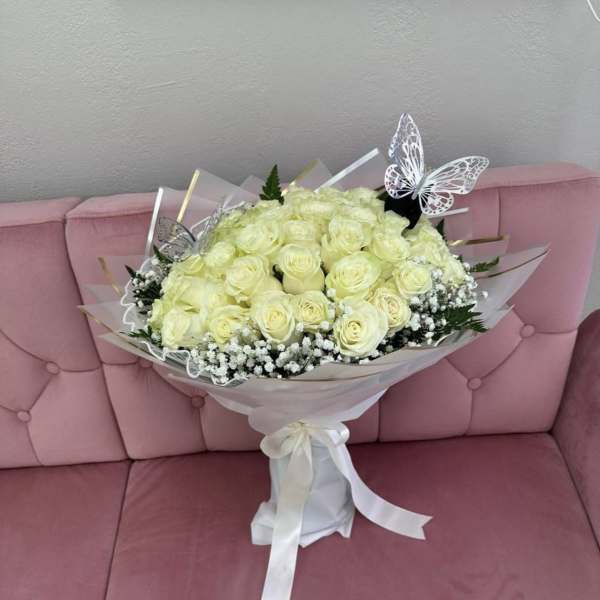 Bouquet of pale yellow roses with butterfly picks and a white ribbon wrap