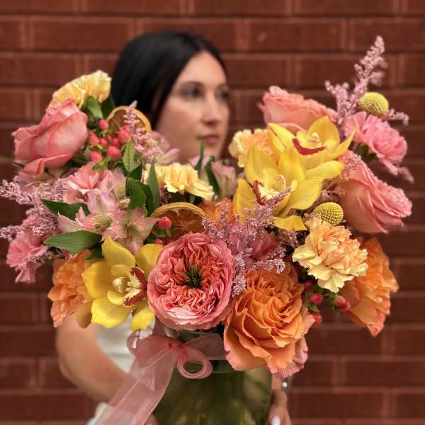 Colorful bouquet of roses, orchids, and carnations in a glass vase