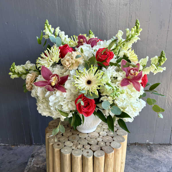 Bouquet of red roses, white hydrangeas, and pink orchids in a white vase