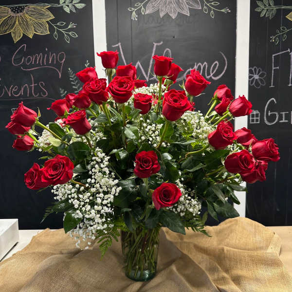 Red roses arranged in a glass vase with white baby's breath.