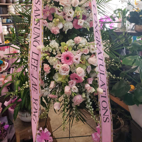 Tall pink and white floral standing spray with ribbon streamers