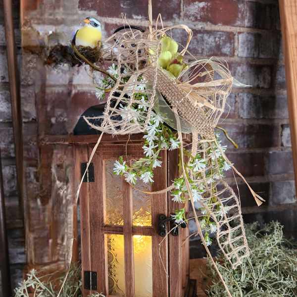 Wooden lantern with white flowers and a small bird decoration