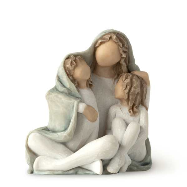Three faceless figurines seated together under a pale green shawl