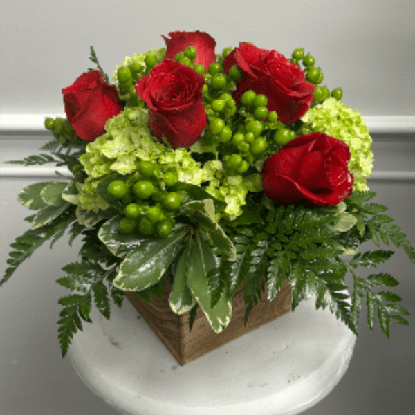 Red roses arranged with green hydrangeas in a square wooden container