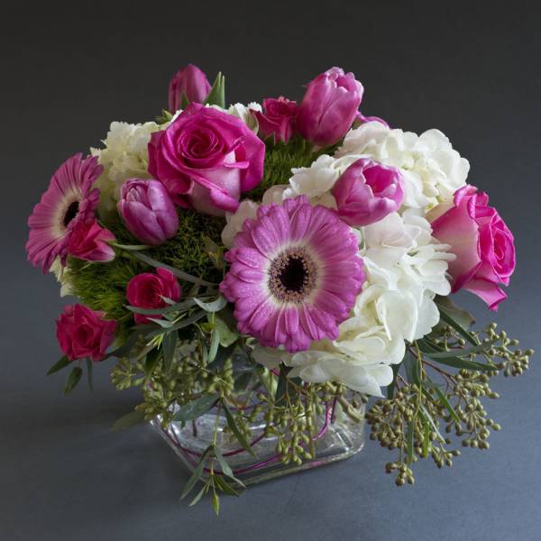 Pink roses and gerbera daisies arranged in a glass vase