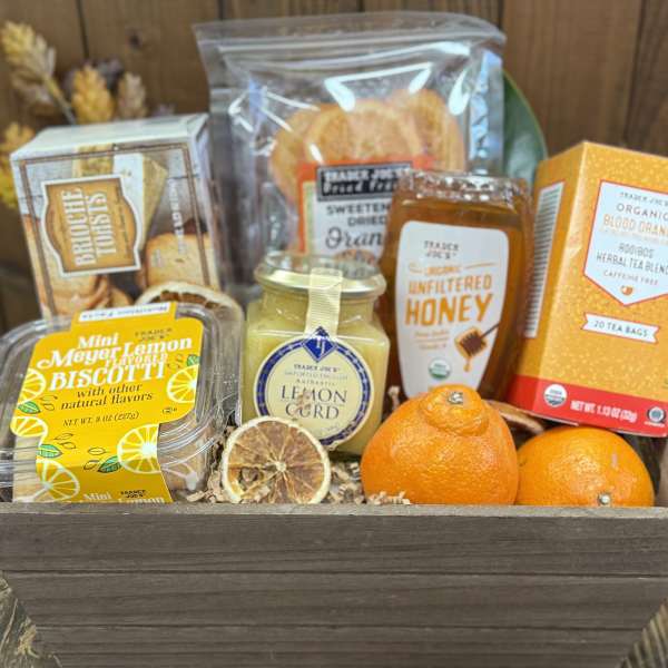 Gift basket with tea, honey, biscuits, lemon curd, and oranges