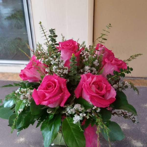 Bouquet of bright pink roses with small white filler flowers