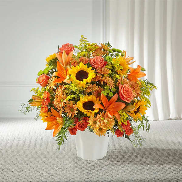 Orange and yellow mixed flower arrangement in a white vase