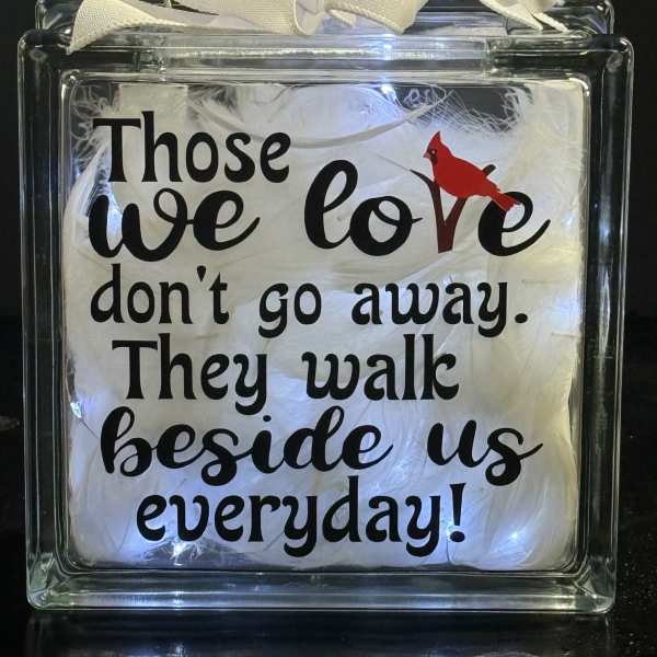 Decorative glass block with a white ribbon and printed quote