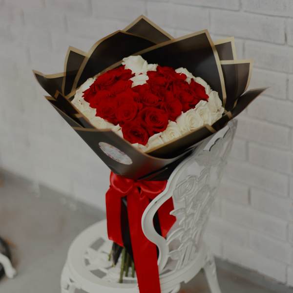 Bouquet of red and white roses wrapped in black paper with a red ribbon