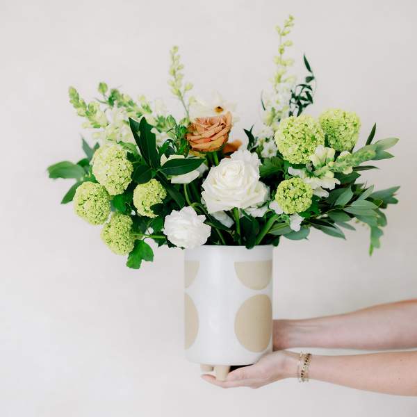 Bouquet of white and peach roses with green blooms in a patterned vase