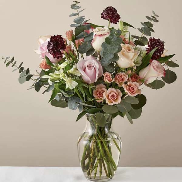 Mixed bouquet of pink and cream roses in a clear glass vase