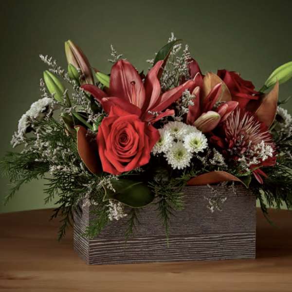 Red floral arrangement in a rectangular wooden box with lilies and roses