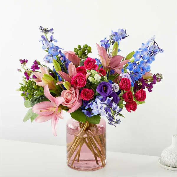 Bouquet of pink and blue flowers in a pink glass vase