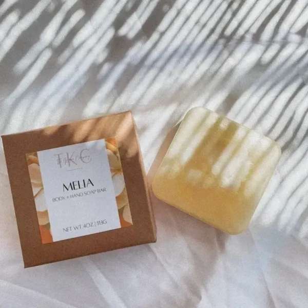 Boxed body and hand soap bar beside a translucent yellow soap bar