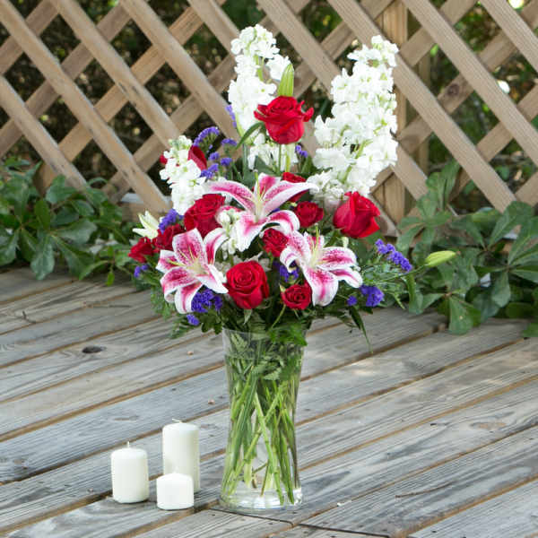 Bouquet of red roses and pink lilies in a clear glass vase