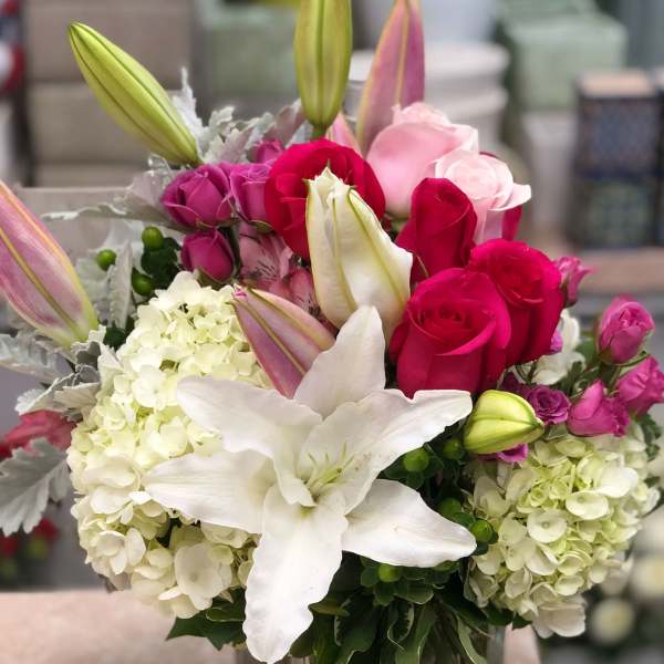 Bouquet of pink and white roses, lilies, and hydrangeas in a glass vase