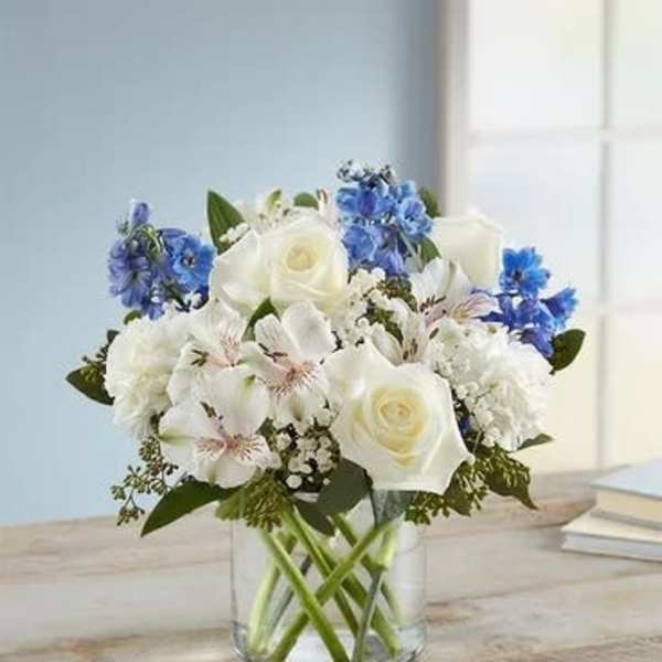 White and blue mixed bouquet in a clear glass vase