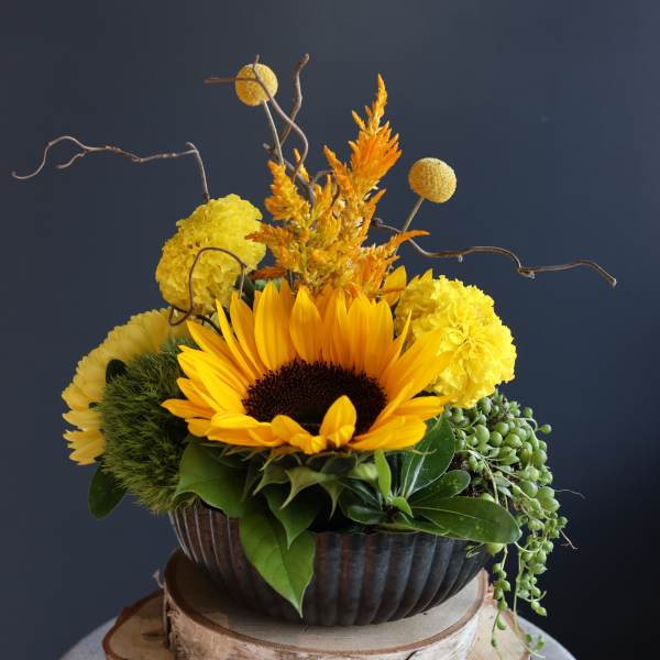 Sunflower arrangement with yellow blooms in a dark bowl vase