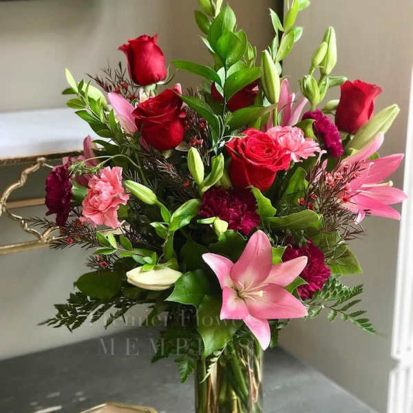Bouquet of red roses, pink lilies, and carnations in a glass vase