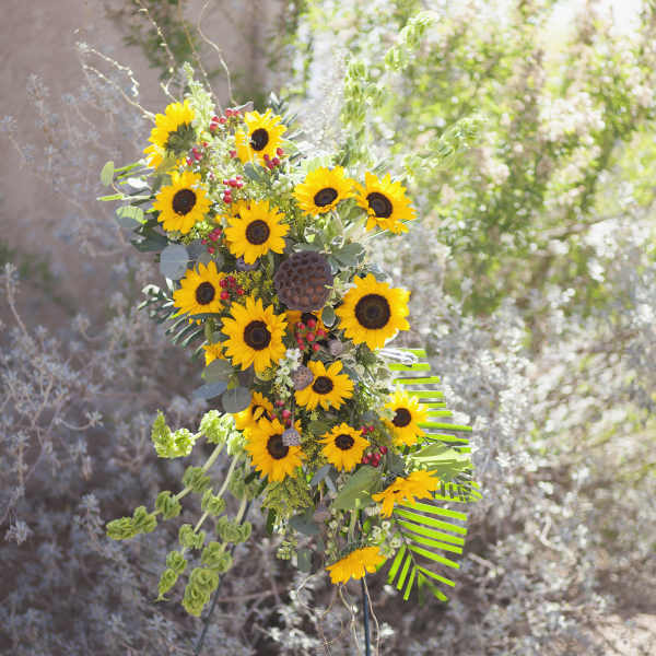Tall sunflower arrangement with mixed greenery and red berry accents