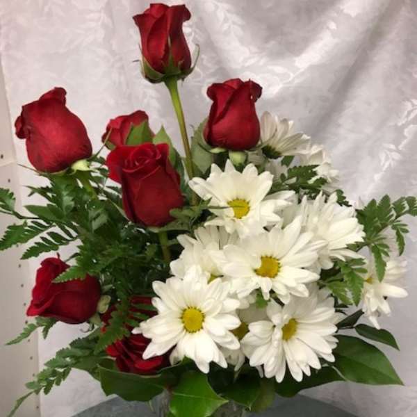 Bouquet of red roses and white daisies in a clear glass vase