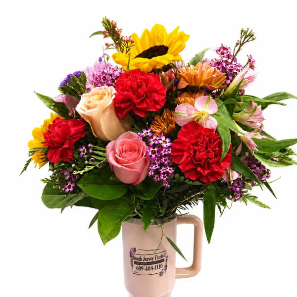Mixed bouquet in a pink handled vase with sunflowers, roses, and carnations