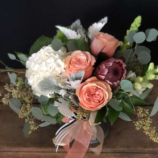 Bouquet of peach roses, white hydrangea, and mixed greenery in a vase
