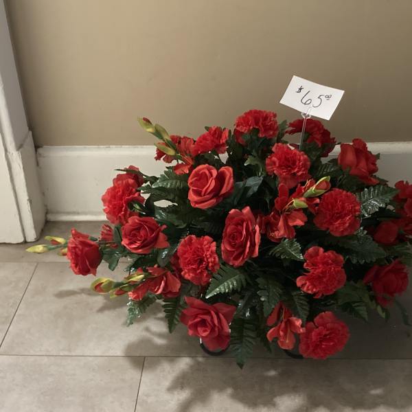 Red rose and carnation arrangement in a low container with a price tag