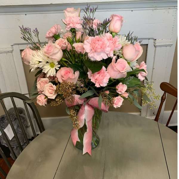 Pink roses and carnations in a glass vase with a pink ribbon
