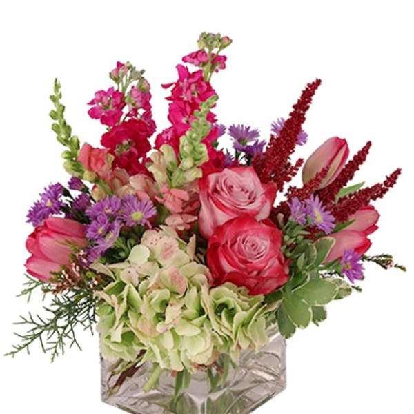 Low pink and purple mixed flower arrangement with hydrangea in a clear glass cube vase