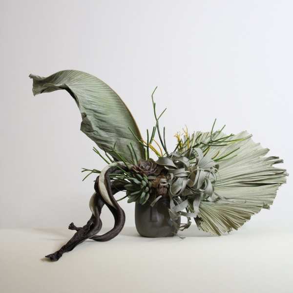 Modern succulent arrangement in a small vase with large dried leaves