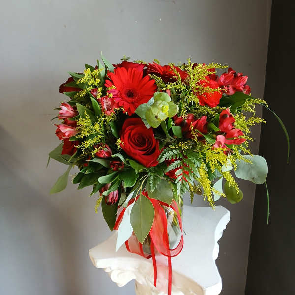 Red rose and gerbera bouquet in a glass vase with ribbon