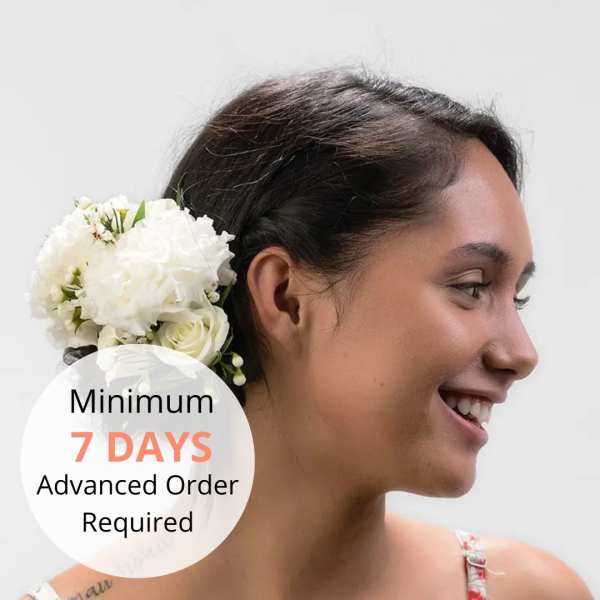 White floral hairpiece of roses and hydrangeas worn in a braided updo.