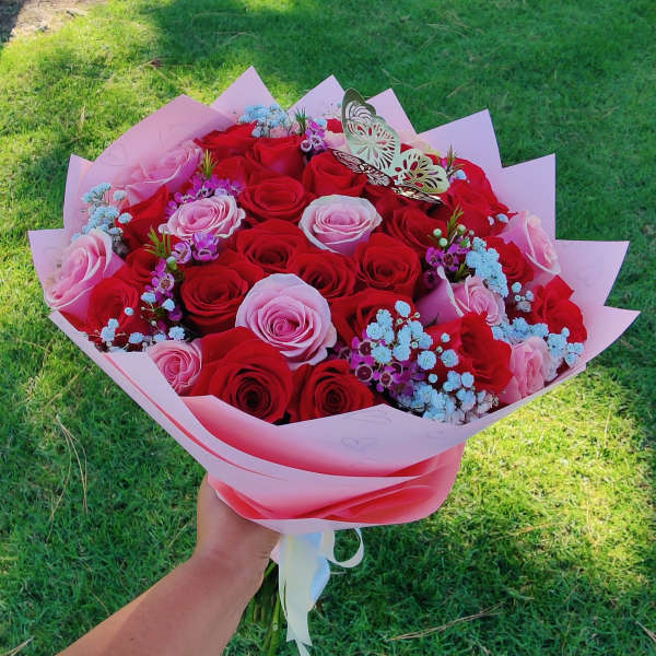Handheld bouquet of red and pink roses with pastel filler flowers