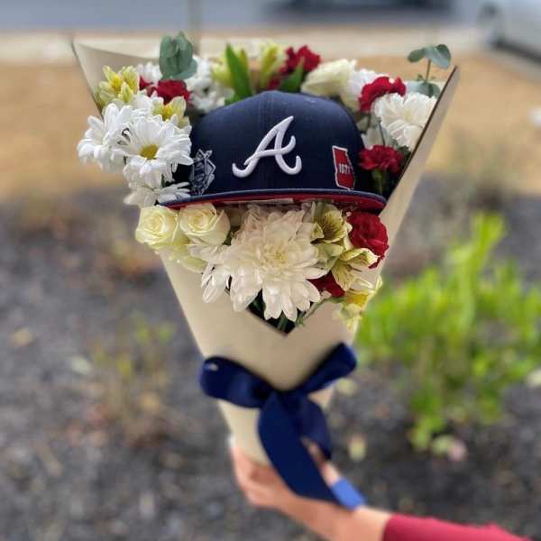 Bouquet with white and red flowers around a navy baseball cap