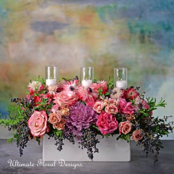 Pink rose arrangement with three glass candle holders in a white rectangular container
