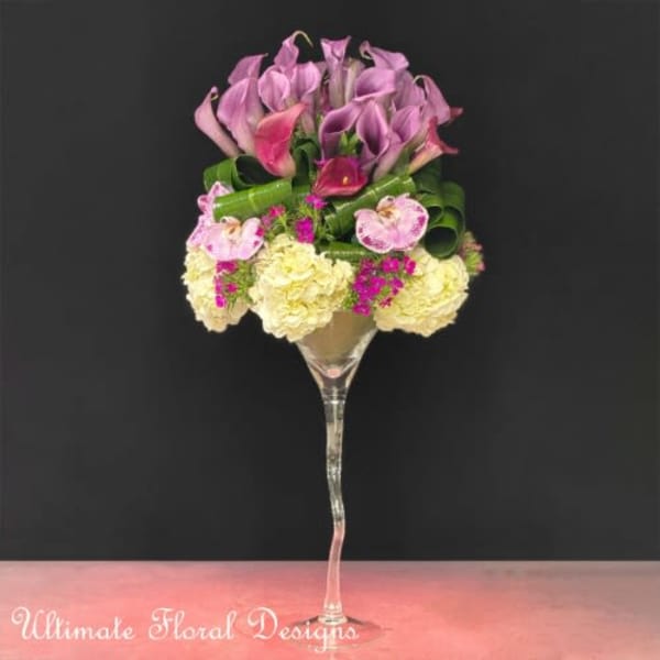 Pink and purple floral arrangement in a tall glass vase