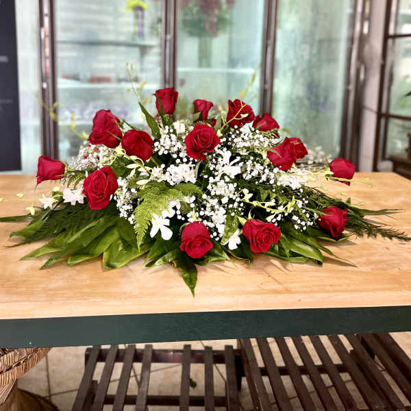 Low floral centerpiece with red roses, white filler flowers, and greenery