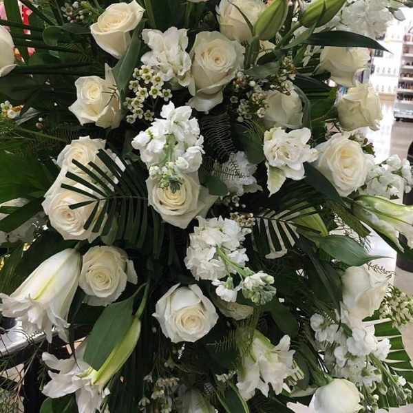 Large white floral standing spray with roses and lilies on an easel