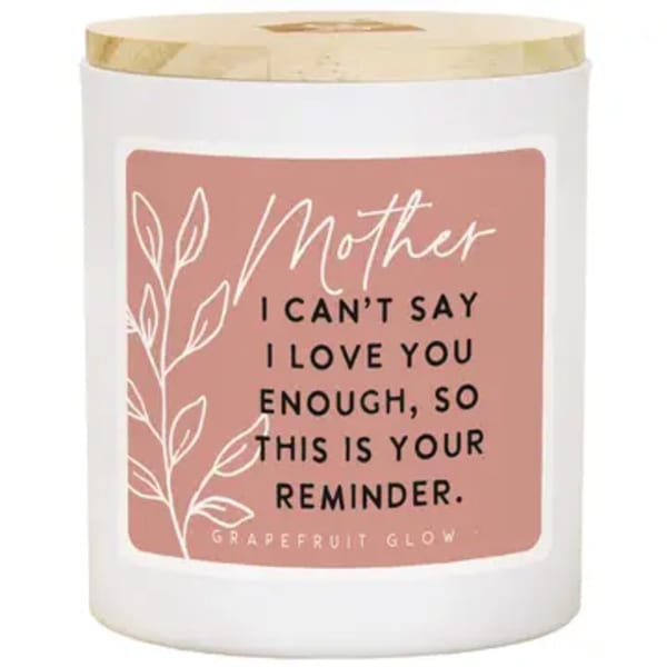 White candle in a glass jar with a pink Mother label and gold lid