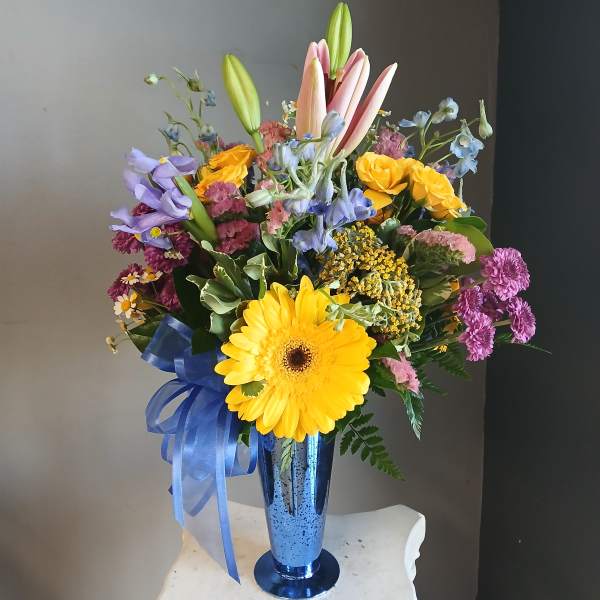 Mixed bouquet with lilies, gerbera daisies, and roses in a blue vase