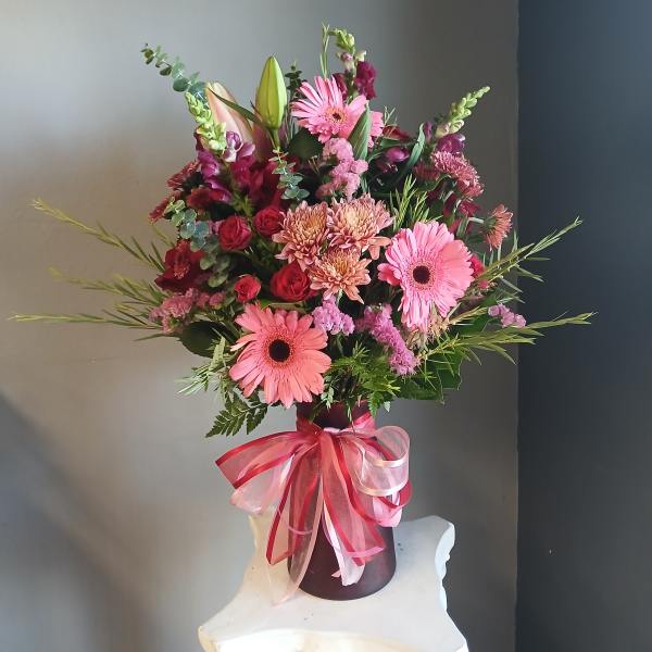 Pink and red mixed bouquet in a vase with a ribbon bow