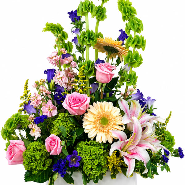 Mixed bouquet in a white square vase with pink, purple, yellow, and green flowers