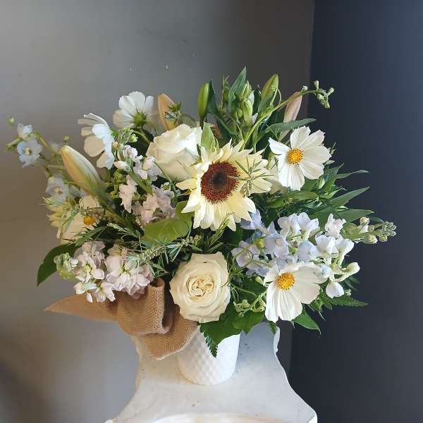 White and pale yellow mixed bouquet in a white vase with burlap wrap